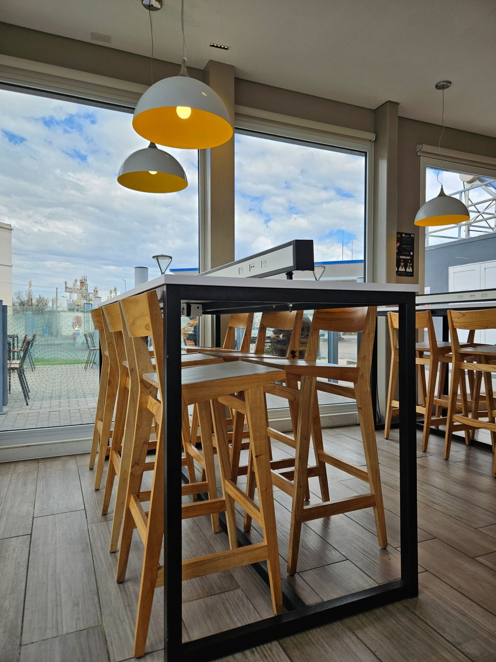 Moderne koffiezaak met houten tafels, hoge krukken en grote ramen